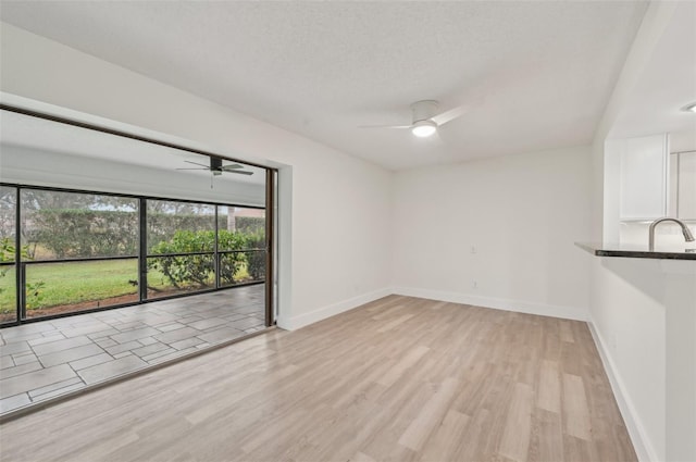 unfurnished room featuring ceiling fan, light hardwood / wood-style flooring, and a textured ceiling