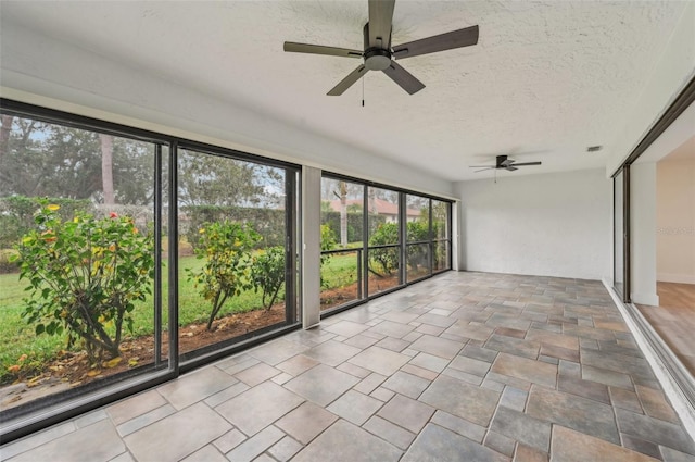 unfurnished sunroom with ceiling fan