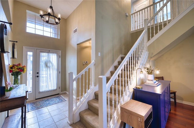 entrance foyer featuring a towering ceiling, tile patterned floors, and a notable chandelier