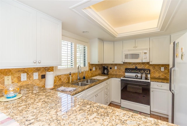 kitchen featuring white appliances, a tray ceiling, sink, and white cabinets