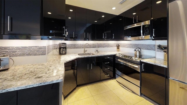 kitchen featuring appliances with stainless steel finishes, tasteful backsplash, sink, light tile patterned floors, and light stone countertops