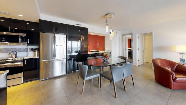 kitchen with appliances with stainless steel finishes, pendant lighting, and light tile patterned floors