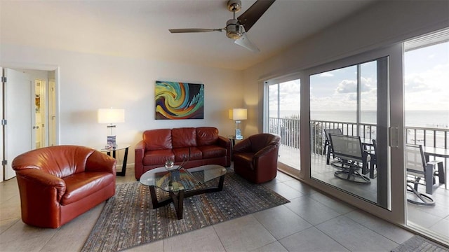 living room with tile patterned floors, ceiling fan, and a water view