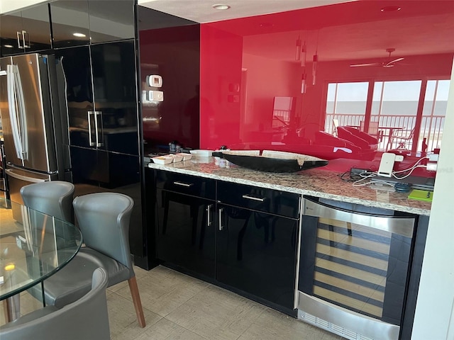 bar with wine cooler, stainless steel fridge, light stone countertops, and ceiling fan