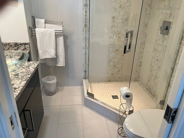 bathroom with tile walls, vanity, walk in shower, toilet, and tile patterned floors