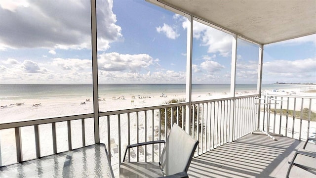 unfurnished sunroom with a view of the beach and a water view