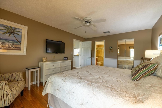 bedroom featuring ceiling fan, ensuite bath, hardwood / wood-style floors, and a textured ceiling