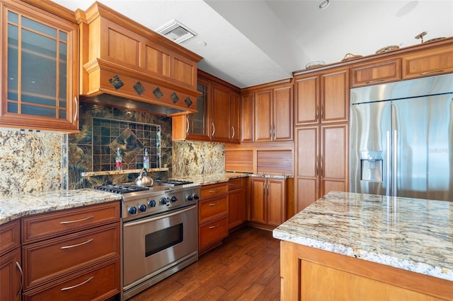 kitchen with backsplash, dark hardwood / wood-style flooring, light stone counters, stainless steel appliances, and custom range hood