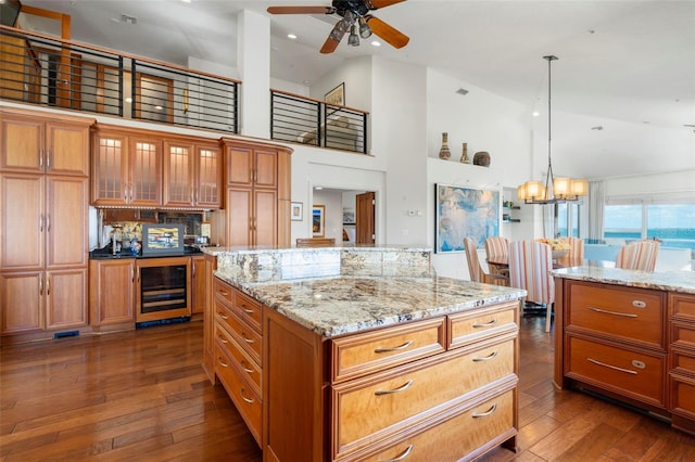 kitchen featuring dark wood-type flooring, decorative light fixtures, a kitchen island, beverage cooler, and ceiling fan with notable chandelier