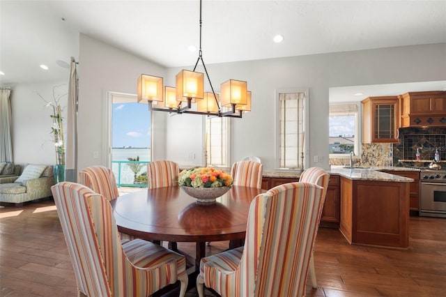 dining area featuring dark wood-type flooring, a chandelier, and sink