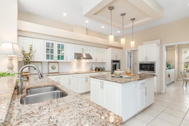 kitchen featuring sink, white cabinetry, light stone countertops, built in microwave, and a raised ceiling