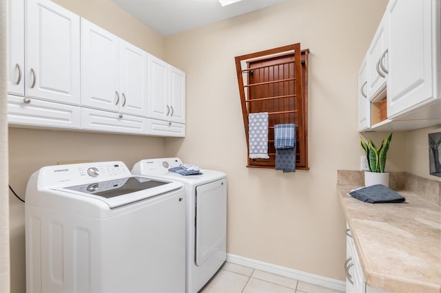 laundry room featuring light tile patterned flooring, cabinets, and washing machine and clothes dryer