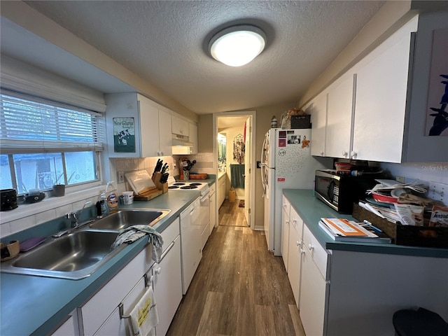 kitchen featuring sink, white cabinetry, wood-type flooring, a textured ceiling, and white appliances