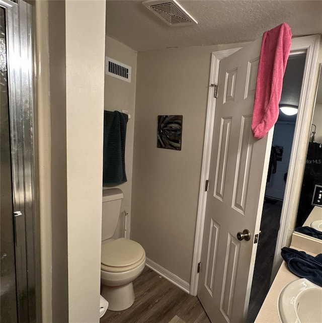 bathroom featuring hardwood / wood-style flooring, vanity, toilet, and a textured ceiling