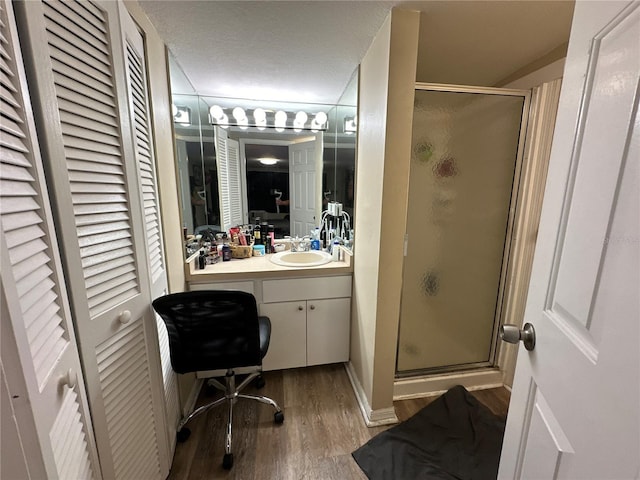 bathroom with vanity, hardwood / wood-style floors, a shower with shower door, and a textured ceiling