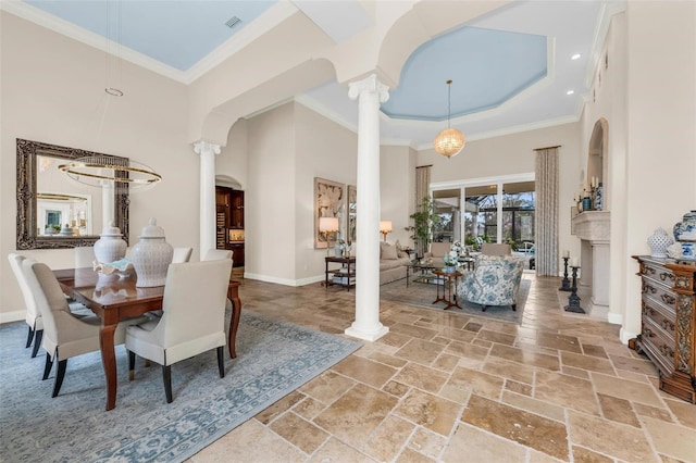 dining area featuring ornate columns, ornamental molding, and a towering ceiling