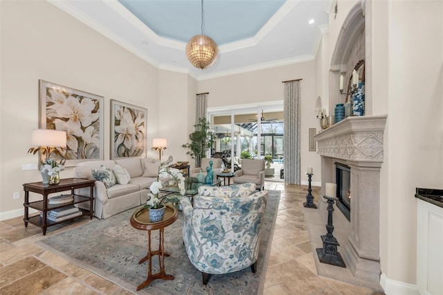 living room with crown molding, a tray ceiling, a fireplace, and a high ceiling