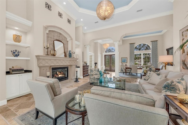 living room with a towering ceiling, ornamental molding, and ornate columns