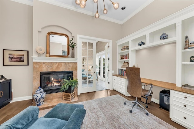 office space with dark wood-type flooring, ornamental molding, a fireplace, and built in desk