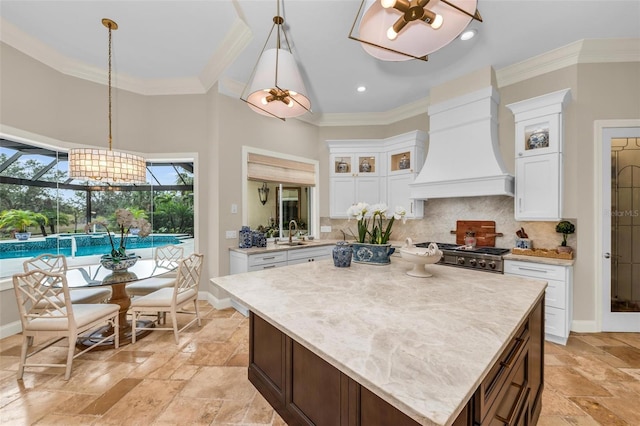 kitchen with hanging light fixtures, a center island, custom range hood, and range