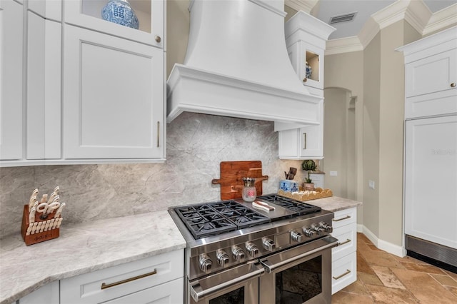 kitchen with range with two ovens, white cabinetry, glass insert cabinets, and custom range hood