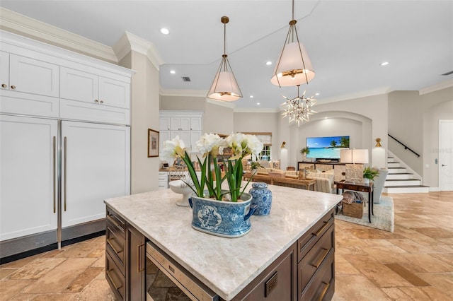 kitchen featuring white cabinetry, crown molding, built in appliances, hanging light fixtures, and a kitchen island