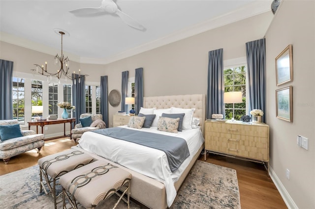 bedroom with crown molding, wood-type flooring, and ceiling fan with notable chandelier