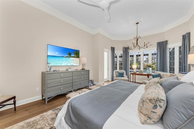 bedroom featuring ornamental molding, ceiling fan with notable chandelier, and light hardwood / wood-style flooring