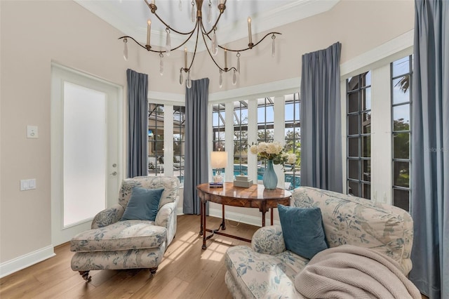 living area featuring a chandelier, light wood finished floors, and baseboards