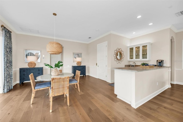 dining space with crown molding and light wood-type flooring