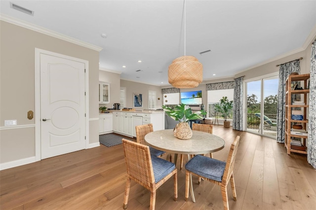 dining area with ornamental molding and light wood-type flooring