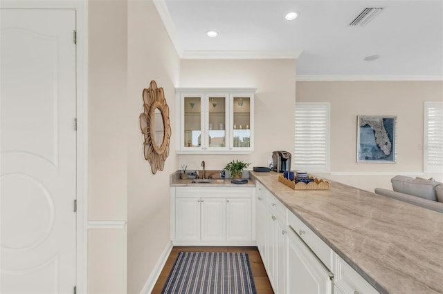 bar with sink, crown molding, dark wood-type flooring, light stone counters, and white cabinets