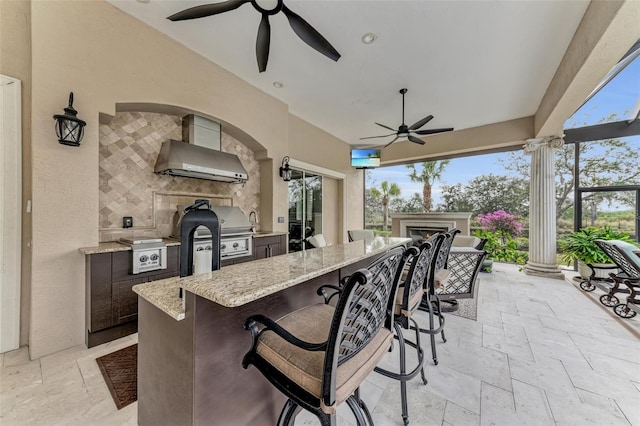 view of patio featuring area for grilling, a grill, ceiling fan, and exterior bar