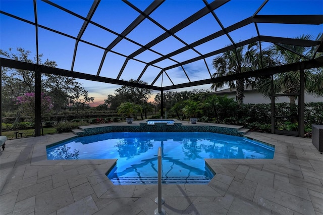 pool at dusk with a patio area, an in ground hot tub, and glass enclosure