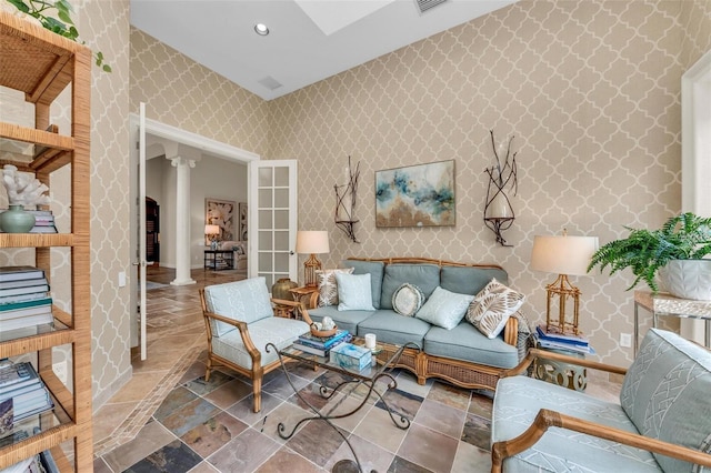 sitting room featuring wallpapered walls, visible vents, stone finish flooring, ornate columns, and recessed lighting