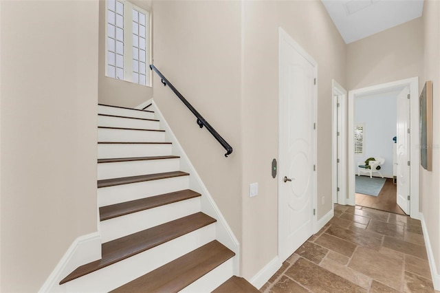 stairway featuring baseboards and stone tile floors