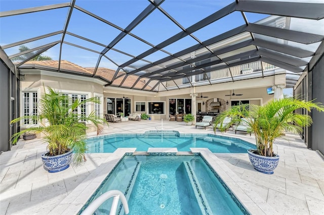 view of swimming pool with glass enclosure, a pool with connected hot tub, a patio area, and a ceiling fan