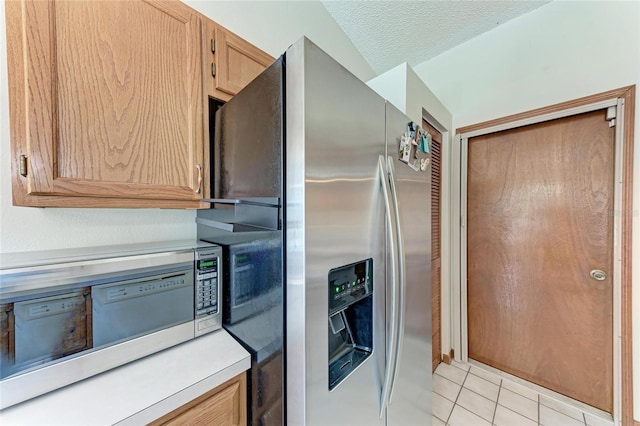 kitchen featuring stainless steel appliances, light tile patterned floors, and a textured ceiling