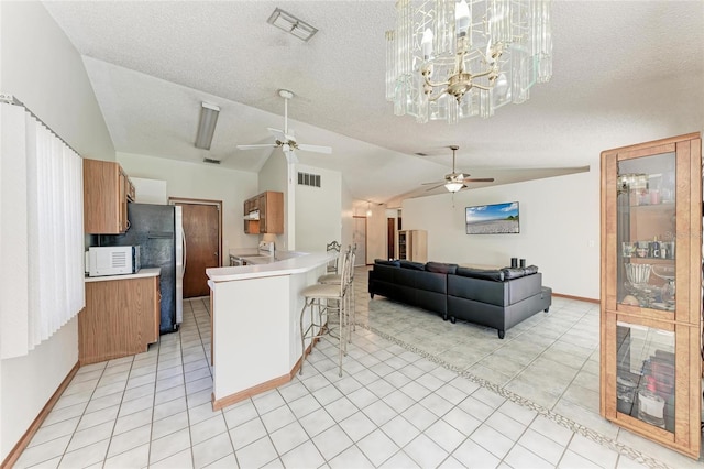 kitchen featuring vaulted ceiling, a breakfast bar, hanging light fixtures, ceiling fan, and kitchen peninsula