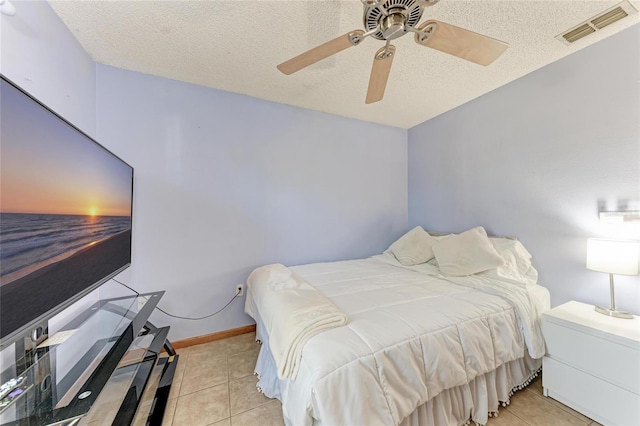 tiled bedroom with ceiling fan and a textured ceiling