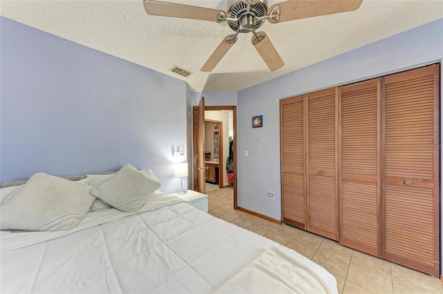 tiled bedroom with ceiling fan, a closet, and a textured ceiling