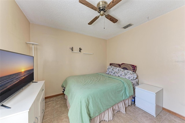 bedroom featuring ceiling fan, light tile patterned floors, and a textured ceiling