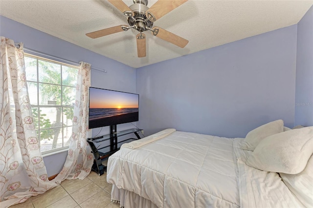 bedroom featuring ceiling fan, a textured ceiling, multiple windows, and light tile patterned floors