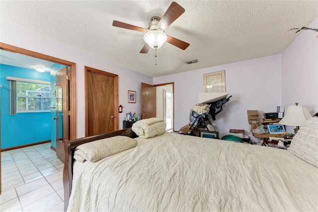 tiled bedroom with ceiling fan and a textured ceiling