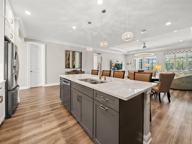 kitchen featuring sink, hanging light fixtures, appliances with stainless steel finishes, a kitchen island with sink, and white cabinets