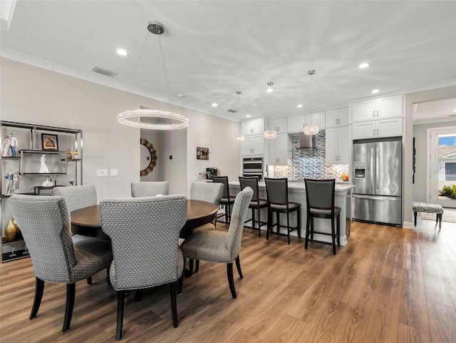 dining room with crown molding and light hardwood / wood-style flooring