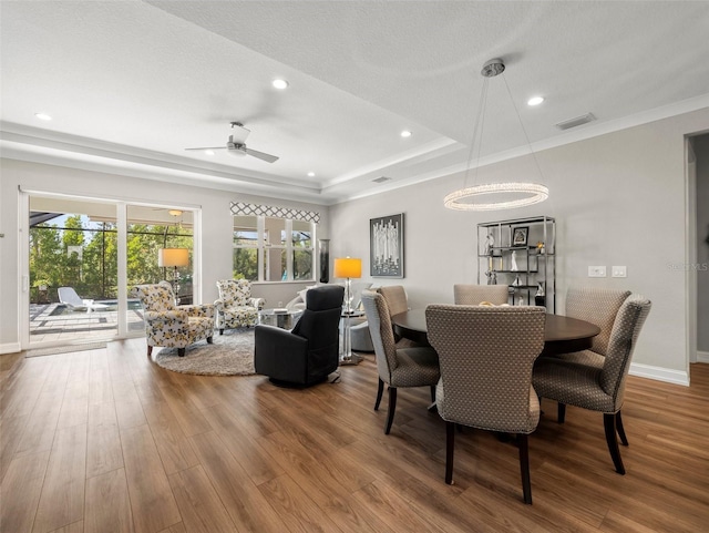 dining area featuring hardwood / wood-style flooring, a raised ceiling, and ceiling fan