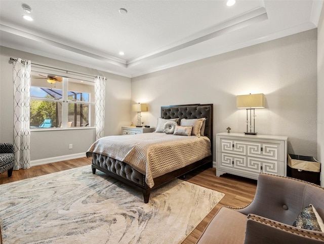 bedroom with a tray ceiling and light wood-type flooring