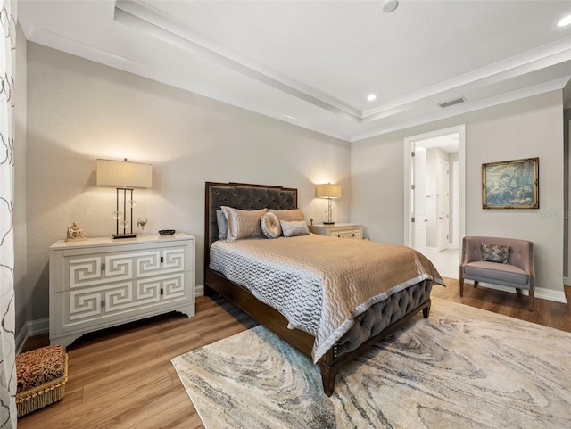 bedroom featuring a raised ceiling and light wood-type flooring