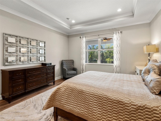 bedroom featuring crown molding, a tray ceiling, and dark hardwood / wood-style flooring